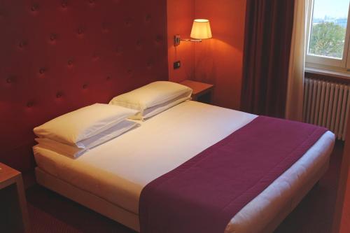 a bed in a room with a red wall at Best Western Hotel Piemontese in Bergamo