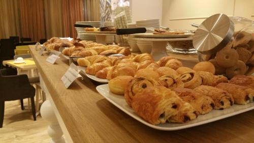 a table filled with different types of pastries on plates at Best Western Hotel Piemontese in Bergamo