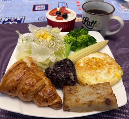Un plato de comida con carne y verduras y una taza de café. en Rainbow B&B, en Dahan