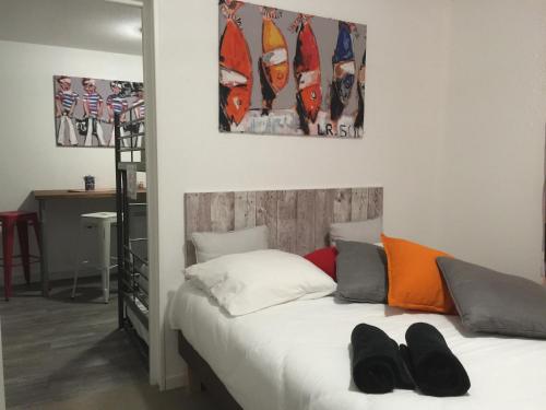 Un dormitorio con una cama con zapatos. en petite pause rochelaise en Aytré