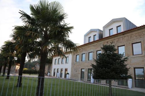 a building with palm trees in front of it at Hotel Rural Quinta das Quintães in Penafiel