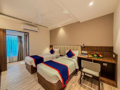 a hotel room with two beds and a desk at Zip by Spree Hotels Shirdi - Walkable Distance from Sai Baba Temple in Shirdi