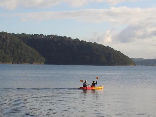 two people sitting on a kayak in the water at scotland island lodge in Church Point