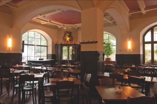 a restaurant with tables and chairs in a room with windows at Hotel Mariandl in Munich