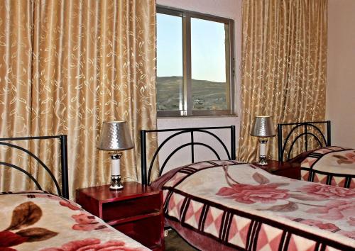 a bedroom with two beds and a window with curtains at Rocky Mountain Hotel Jordan in Petra