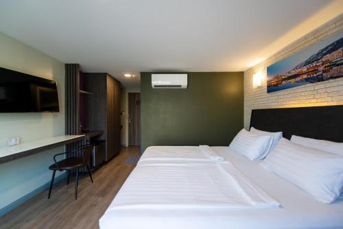 a hotel room with a large white bed and a kitchen at BB Glass House Pattanakrn บีบี กลาสเฮ้าส์ พัฒนาการ in Bangkok