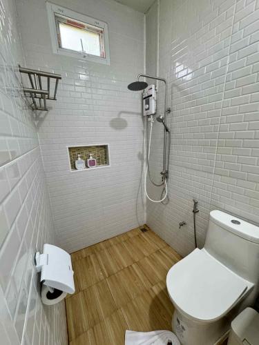 a white bathroom with a toilet and a shower at Khaosok Embrace Resort in Khao Sok National Park