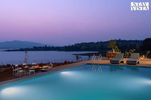 a swimming pool with a view of a lake at StayVista at Crimson Bleu - Bonfire & Pet Friendly in Pune