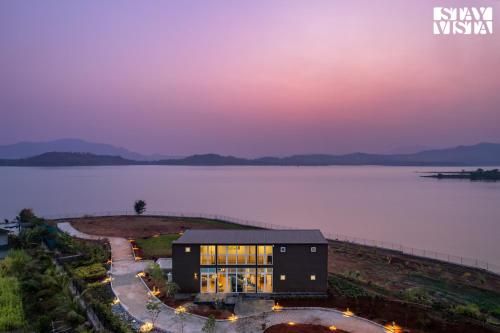 a house on the shore of a lake at night at StayVista at Crimson Bleu - Bonfire & Pet Friendly in Pune
