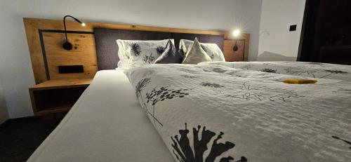 a bedroom with a large white bed with a wooden headboard at Haus Enzian Apartments in Kartitsch