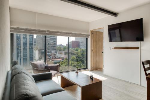 a living room with a couch and a large window at Myla Roma Norte in Mexico City