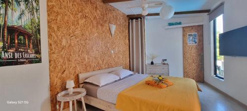 a bedroom with a bed with a yellow bedspread at Bungalow Zananas charme et Authenticité chez l'habitant in Saint-Paul