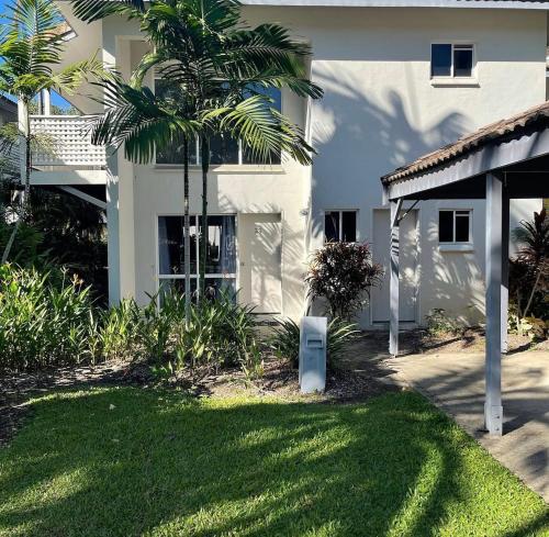 a palm tree in front of a white house at Tropical Palms Port Douglas in Port Douglas