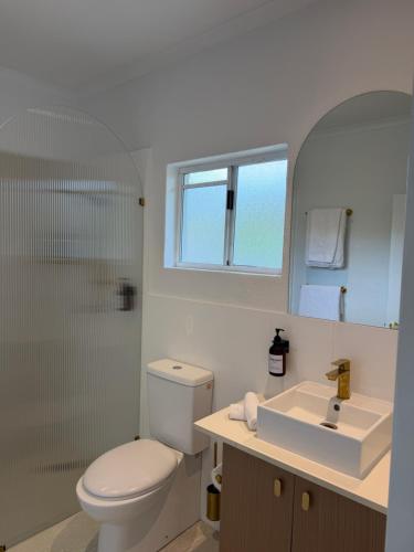 a white bathroom with a toilet and a sink at Tropical Palms Port Douglas in Port Douglas