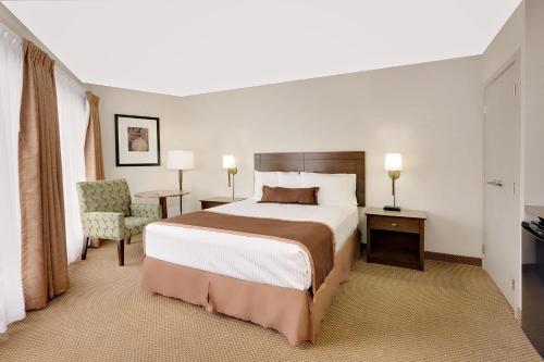 ein Hotelzimmer mit einem Bett und einem Stuhl in der Unterkunft Ramada by Wyndham Kamloops in Kamloops