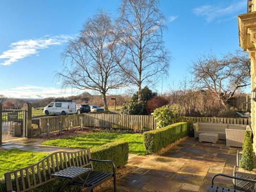 a yard with two benches and a fence at Bracken Hall House in Baildon
