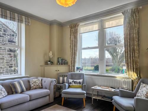 a living room with a couch and chairs and windows at Bracken Hall House in Baildon