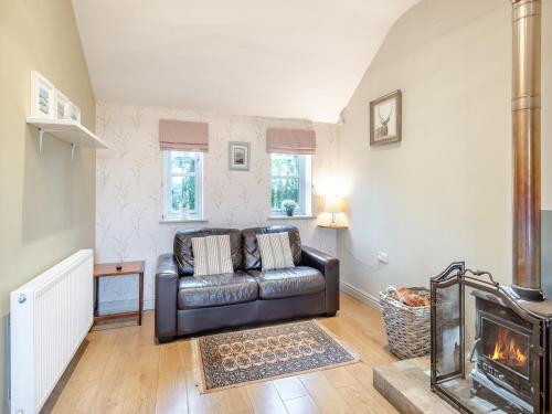 a living room with a leather couch and a fireplace at Walnut Cottage - Ukc6632 in Pentney