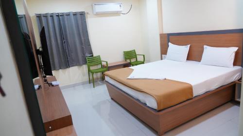 a bedroom with a bed and two green chairs at Vijaya Inn in Visakhapatnam