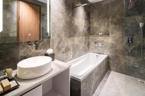 a bathroom with a sink and a bath tub at Foxtrail Sector 60 - AM Hotel Kollection, Gurgaon in Gurgaon