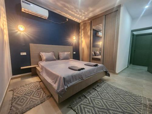a bedroom with a large bed with a tv on the wall at Jasmin Prestige Duplex - Hammamet in Hammamet