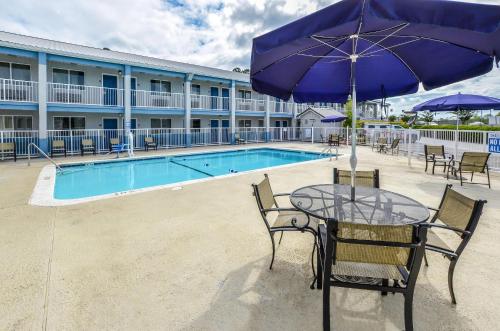 a table with an umbrella next to a pool at Rodeway Inn North Charleston - Ashley Phosphate in Charleston