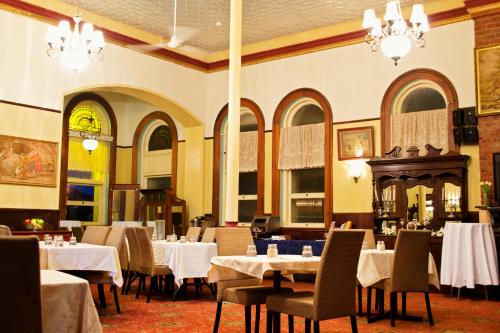 un comedor con mesas, sillas y lámparas de araña en Criterion Hotel-Motel Rockhampton en Rockhampton