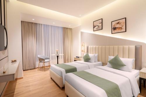 a hotel room with two beds and a television at Foxtrail Sector 60 - AM Hotel Kollection, Gurgaon in Gurgaon