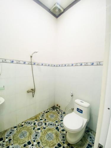 a bathroom with a toilet and a tiled floor at Quốc Hưng in Ấp Trà Cô