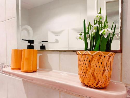 a bathroom counter with two vases and flowers on it at One Guest Place Deluxe Room near the Beach in Abu Dhabi