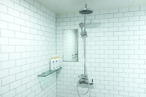 a shower in a white tiled bathroom with a mirror at Orago Stay Hotel in Suwon