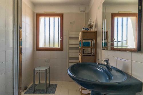 a bathroom with a large blue sink and two windows at Le mas clair in Pins-Justaret