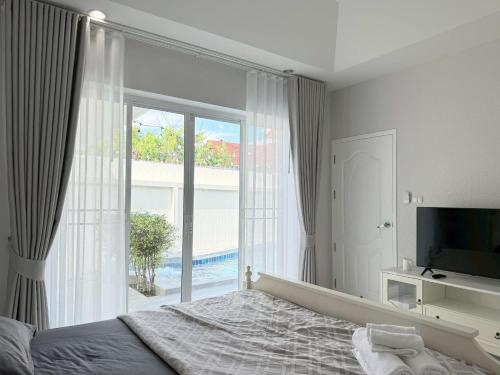 a bedroom with a bed and a large window at Buddy pool villa in Nong Prue