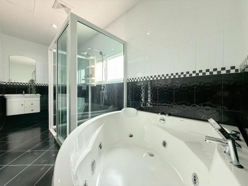 a white bath tub in a bathroom with a mirror at Buddy pool villa in Nong Prue