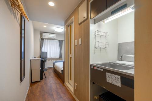 a small room with a sink and a bed at Sleep Inn Gotanda in Tokyo