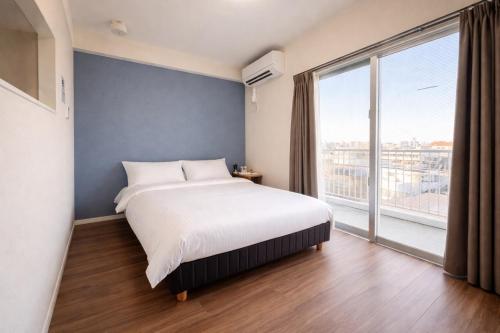 a bedroom with a large bed and a large window at Condominium GOLF GOLF Tsuboya in Naha