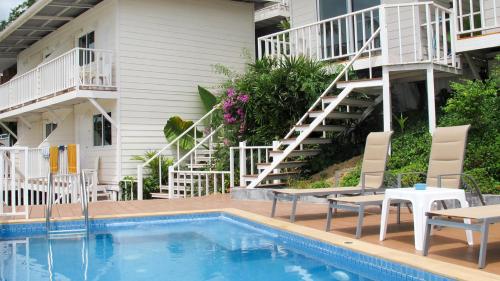 a hotel with a swimming pool and chairs and stairs at Uphill Cottage in Phi Phi Islands