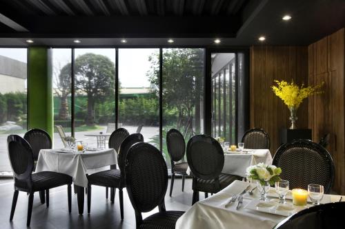 a restaurant with white tables and chairs and large windows at Holly Wood Motel in Pitou
