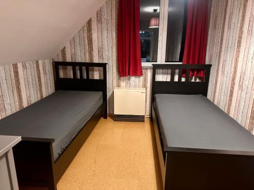 two beds in a small room with red curtains at Ferienhaus Isaro in Ludwigsburg