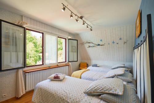 two beds in a bedroom with two windows at les bois de saint auvent in La Geneytouse