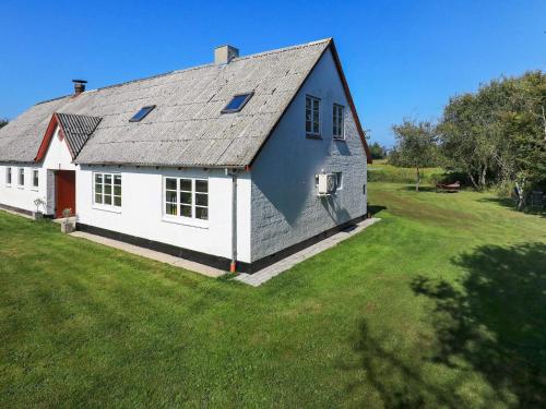 a white house with a gray roof on a green field at 6 person holiday home in Hjørring in Hjørring