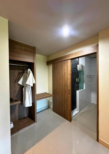 a bathroom with a walk in shower and a wooden door at Akelada Hotel in Nang Rong
