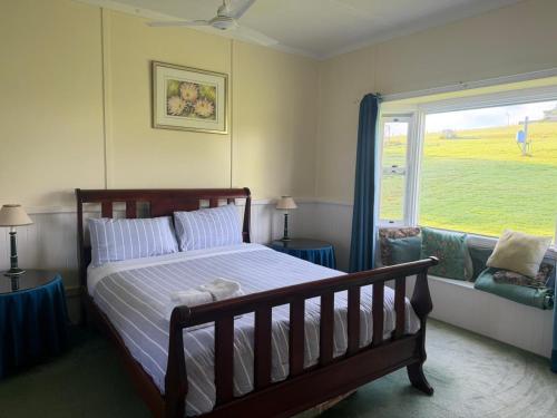 a bedroom with a bed and a large window at Fernbrook Lodge in Dorrigo