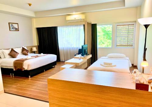 a hotel room with two beds and a desk at Akelada Hotel in Nang Rong