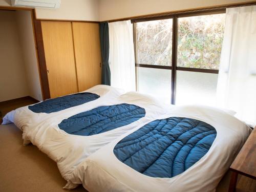 a bed in a room with a large window at Vegestay Nonaka in Tanabe