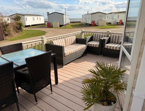 a deck with chairs and a table and a table and chairs at Stylish Inviting 2 Bedroom Caravan with Sea View in East Mersea