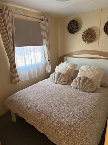 a bedroom with a bed with two pillows and a window at Shell Beach Holiday Home Mersea Coopers Beach in East Mersea