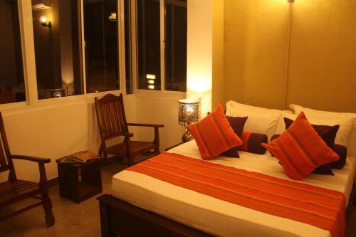 a bedroom with a bed with orange and white pillows at Dumbara Peak Residence in Kandy
