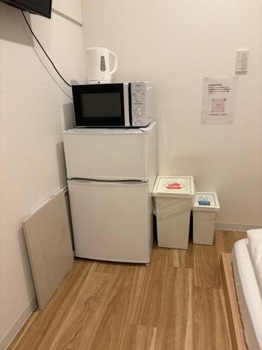 a kitchen with a microwave on top of white cabinets at コインズホステル天神ペット宿泊可 in Fukuoka