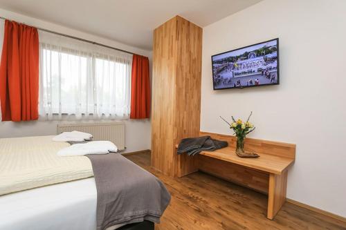 1 dormitorio con 1 cama y un jarrón de flores sobre una mesa en Appartement Popelka, en Saalfelden am Steinernen Meer